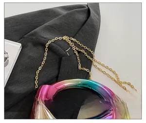 Detail of colorful gradient acrylic handbag with a refined golden metal chain strap