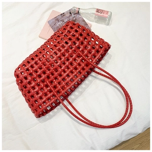 Detailed close-up of a red woven tote bag with hollow-out cross patterns on white fabric