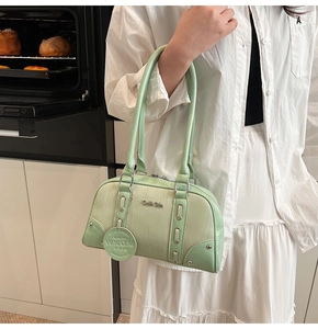 Side view of a light green Boston shoulder bag with wood grain texture and metal charms