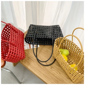 Detailed view of woven tote bags in red, black and brown on a wooden bench