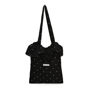 Floral black tote bag with white ruffles and Magic Pocket label on plain white backdrop