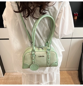 Detail of mint green Boston bag with wood-grain texture and silver chain tag worn by a model
