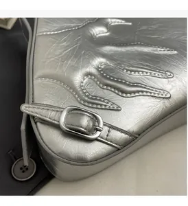 Detail of silver metallic leather bag with flame stitching and polished metal buckle