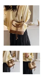 Detail view of woven straw bucket bag featuring dark brown leather strap and drawstring closure