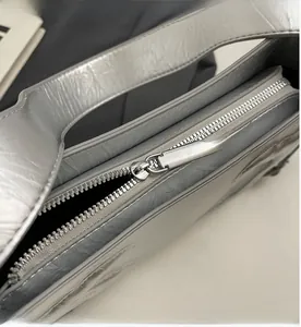 Close-up of silver baguette bag showing smooth metal zipper and crinkled leather texture