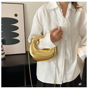 Close-up of a sculpted gold metallic clutch bag with a sleek chain and mirrored finish
