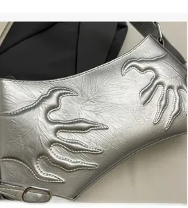 Close-up of silver shoulder bag showing claw-shaped embossed stitching and pleated texture