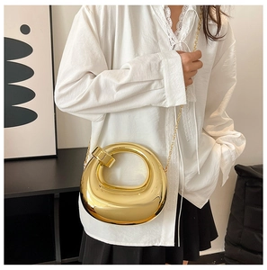 Mirror-finish gold geometric clutch held by model with elegant metal chain strap
