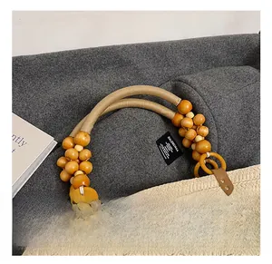 Detail of woven straw tote featuring wooden bead handle and yellow ring connector