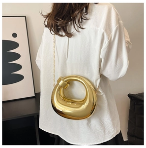 Close-up of golden irregular hollow ring evening bag with metallic finish and chain