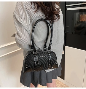 Detail of black wavy texture handbag with silver round tag and polished handles