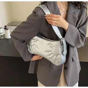 Close-up of silver baguette bag featuring flame relief texture and metallic finish