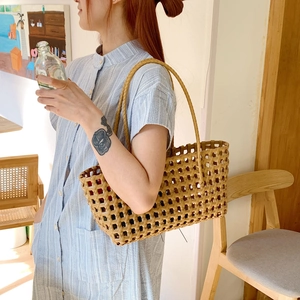 Fashionable hollow woven straw tote bag with round shoulder straps on model in cafe setting