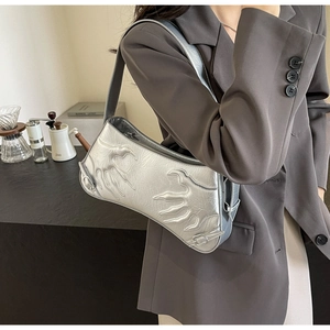 Detailed view of silver baguette bag with embossed flame pattern and metallic finish