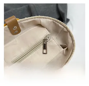 Detail of woven beach bag interior featuring beige lining and silver metal rivets