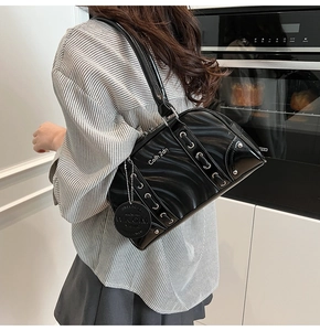 Close-up of black patent leather shoulder bag with silver eyelets and punk style details