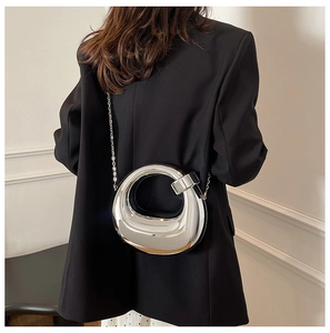 Detail of silver metallic hollow round clutch with chain strap on a model