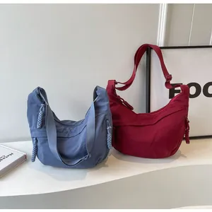 Detail of nylon dumpling bags in blue and burgundy with adjustable woven zipper pulls
