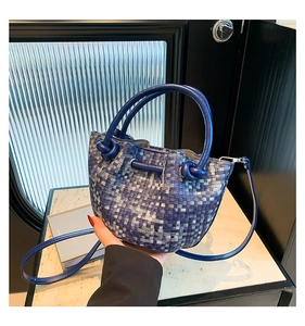 Close-up of blue woven bucket bag featuring unique knotted handles and drawstring closure
