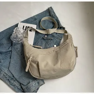 Detail of beige crescent dumpling bag with woven rope zipper and adjustable strap