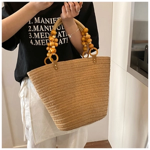 Detail of hand-woven straw tote with elegant wooden bead handles and natural texture