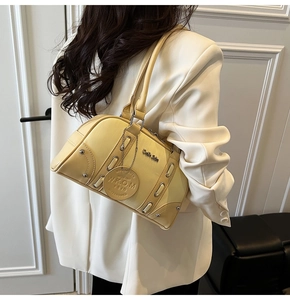 Detail of butter yellow Boston shoulder bag with silver studs on a stylish cream blazer