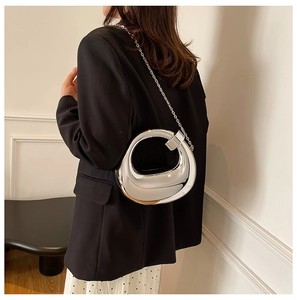 Close-up of a silver mirror acrylic handbag with a slim metal chain and sleek design