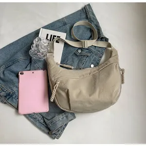 Detail of beige nylon crescent bag with adjustable strap and lifestyle accessories