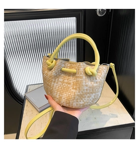 Detail of woven bucket bag with yellow round handles and a drawstring closure