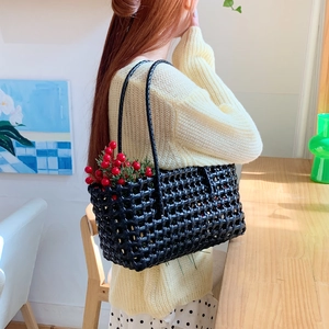 Fashionable black hollow woven shoulder bag for women styled in a cozy indoor setting