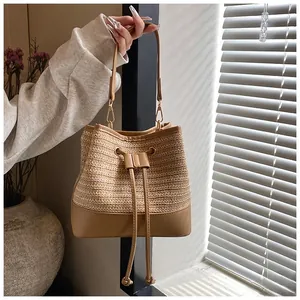 Detail of a straw bucket bag with leather base and drawstring closure in natural lighting