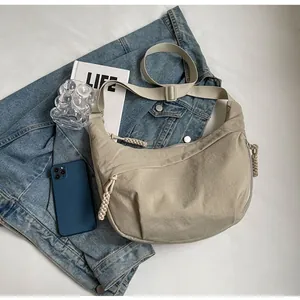 Detailed shot of beige nylon crescent bag with woven rope zipper and adjustable strap