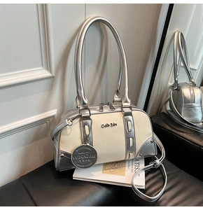 Close-up of contrast color Boston bag with silver metallic finish and branded charm