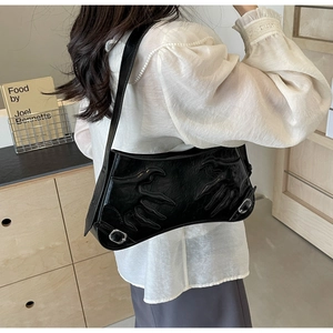 Detail of black glossy leather shoulder bag with unique claw-mark embossed design