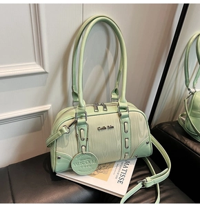 Detail of mint green Boston bag with wood texture paneling and polished metal logo tag