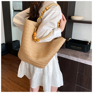 Detail of hand-woven straw bucket bag featuring a natural beaded handle for women