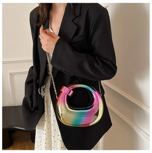 Chic iridescent acrylic shell bag with golden metal chain strap worn by a model