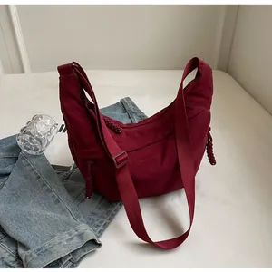 Detail of burgundy canvas crescent bag with textured strap and woven zipper pull