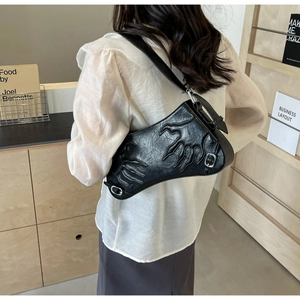 Detail of black saddle bag featuring embossed flame patterns and metallic buckle on shoulder