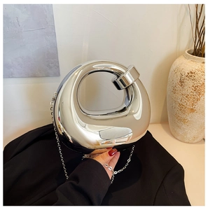 Close-up of a silver mirror-finish spherical clutch bag with a metallic chain strap