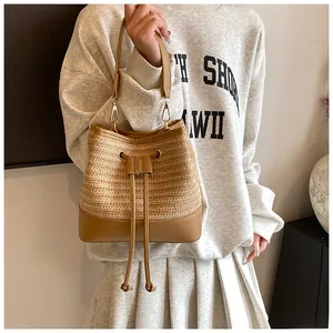 Detail of straw bucket bag featuring PU leather drawstring closure and gold hardware hooks