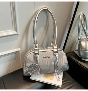 Detailed macro view of the silver Boston bag showing smooth metallic texture and round charm