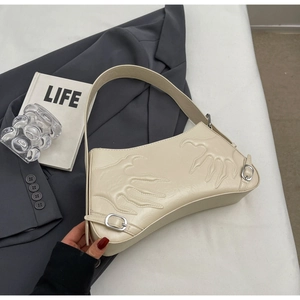 Detail of creamy white underarm bag with 3D paw relief and silver buckles on a grey blazer