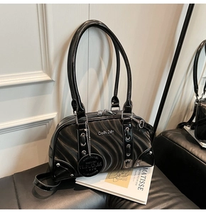 Detail of glossy black patent leather boston bag with wave patterns and silver studs