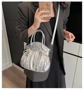 Close-up of silver pleated crossbody bag with pearl charm and metal logo detail