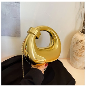 Detail of a hollow teardrop evening clutch with a polished gold mirror finish and chain