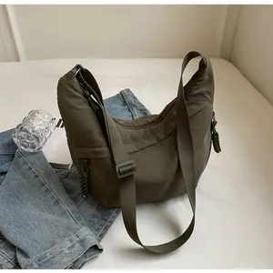 Detail of army green nylon crescent bag with adjustable strap and braided zipper pull