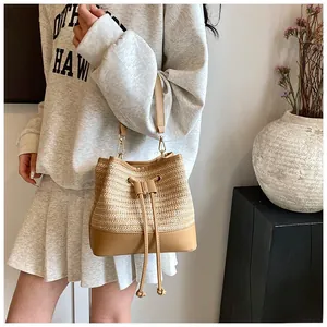 Detail of woven straw bucket bag showing drawstring closure and synthetic leather base