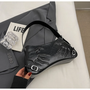 Detail of black leather baguette bag featuring embossed flame patterns and silver buckle