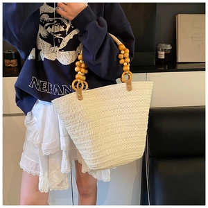 Detail of hand-woven straw tote with elegant dark wood bead handle and leather accents
